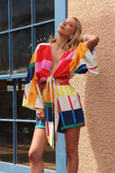 Woman wearing a colorful outfit leaning against a wall.