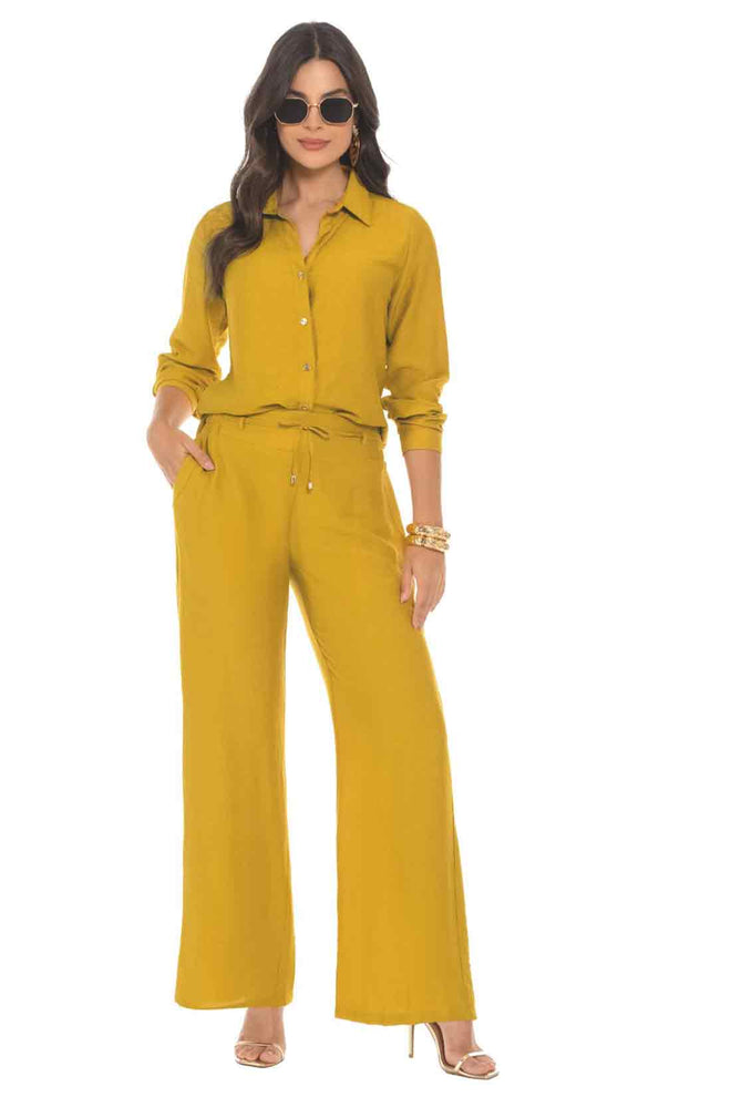 Woman wearing a mustard yellow jumpsuit on a white background