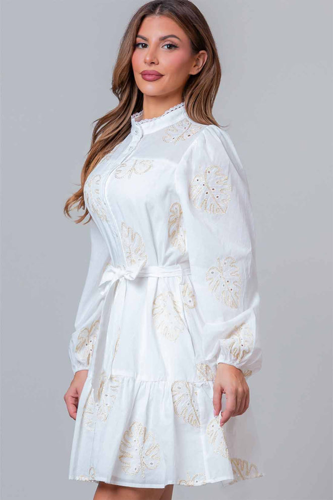 Woman wearing a white dress with floral lace details on a gray background