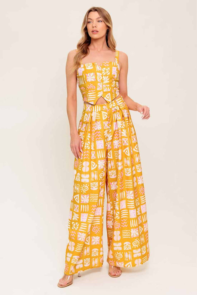 Woman wearing a yellow patterned jumpsuit on a white background