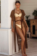 Woman in a beige bikini and brown cover-up standing indoors.