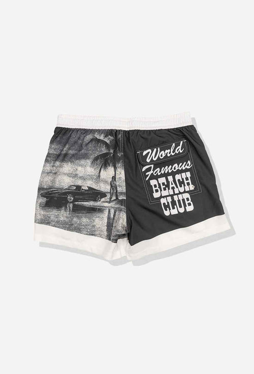 Black shorts with a palm tree and car graphic on one side and 'World Famous Beach Club' text on the other, on a white background.